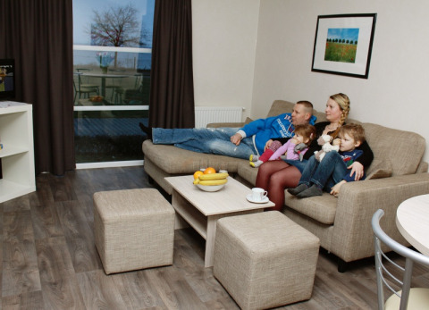 Familia relajándose en la sala de una casa de glamping en Vakantiepark Ostseecamping Zierow, Alemania.