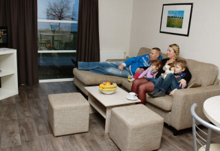 Gezin ontspant in de woonkamer van glamping accommodatie op Vakantiepark Ostseecamping Zierow, Duitsland.