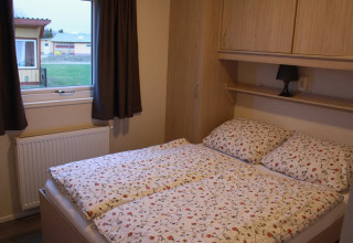 Camera da letto con biancheria floreale in una cabina di legno al Vakantiepark Ostseecamping Zierow, Germania.