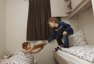 Dos niños juegan en camas acogedoras dentro de un alojamiento moderno en Ostseecamping Zierow en Alemania.