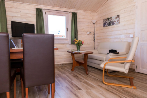 Interieur van een glampingaccommodatie bij Vakantiepark Ostseecamping Zierow met bank, tafel en stoelen.