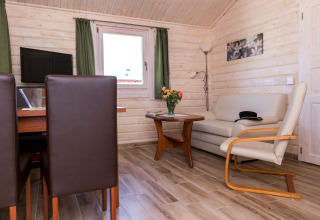 Interior view of cozy glamping cabin at Vakantiepark Ostseecamping Zierow with sofa, table, and chairs.