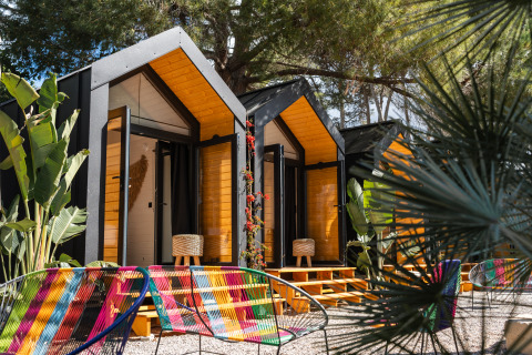 Kleurrijke glampingaccommodatie met moderne hutten en stoelen bij Camping Parco Ibiza by San Antonio, Ibiza.