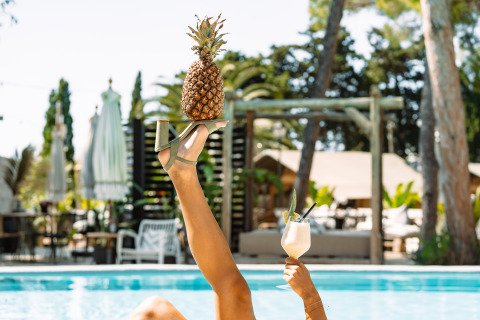 Ontspannen bij het zwembad van Camping Parco Ibiza by San Antonio met een ananas op een sandaal en cocktail.