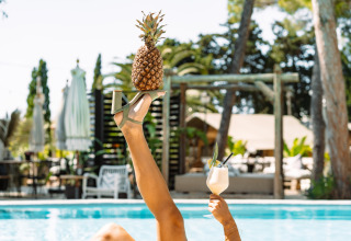 Ontspannen bij het zwembad van Camping Parco Ibiza by San Antonio met een ananas op een sandaal en cocktail.