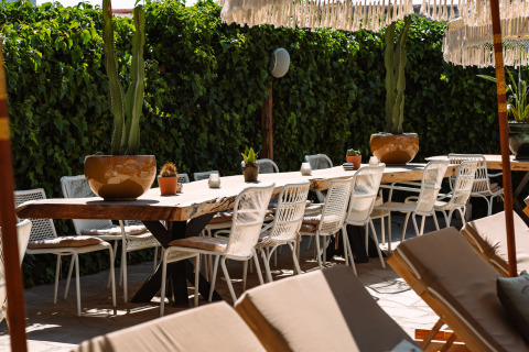 Buiten eethoek met houten tafel, witte stoelen en cactussen bij Camping Parco Ibiza by San Antonio, Glamping Ibiza