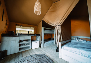 Interieur van een glampingtent bij Camping Parco Ibiza met stapelbedden, kitchenette en knusse sfeer.