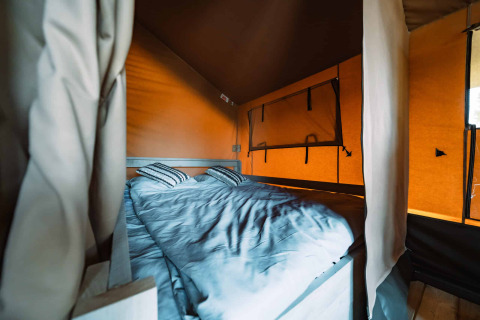Interieur van een gezellige slaapruimte met tweepersoonsbed in een glamping tent bij Camping Parco Ibiza.