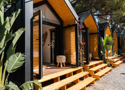Rij moderne glampinghutten met open glazen deuren en houten traptreden bij Camping Parco Ibiza, San Antonio.
