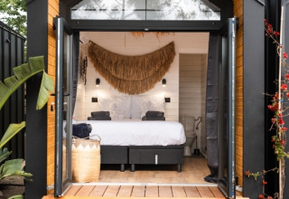 Moderne glampingaccommodatie bij Camping Parco Ibiza, met open deuren, comfortabel bed en natuurlijke decoratie.