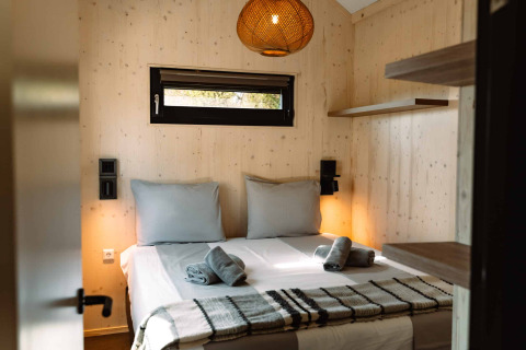 Slaapkamer in glamping-accommodatie met tweepersoonsbed en houten muren bij Camping Parco Ibiza nabij San Antonio.