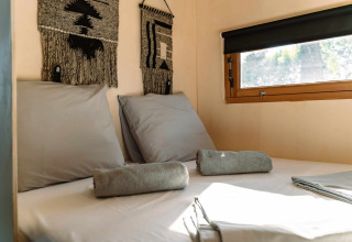 Knus bed met grijs beddengoed en handdoeken in een glamping tent bij Camping Parco Ibiza, San Antonio, Ibiza.