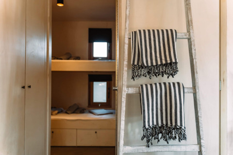 Interieur van Camping Parco Ibiza glamping met stapelbedden, ladder en gestreepte handdoeken.