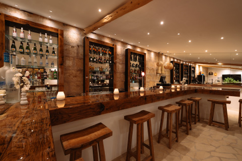 Rustieke bar met houten krukken en flessen bij Camping Parco Ibiza by San Antonio - Glamping Ibiza.
