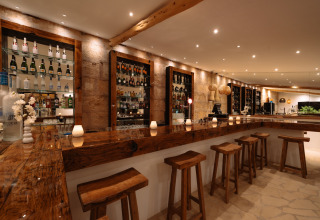 Rustieke bar met houten krukken en flessen bij Camping Parco Ibiza by San Antonio - Glamping Ibiza.