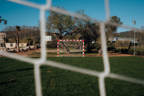 Uitzicht door het doelnet op het voetbalveld en de groene omgeving bij Camping Parco Ibiza by San Antonio.