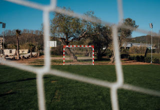 Uitzicht door het doelnet op het voetbalveld en de groene omgeving bij Camping Parco Ibiza by San Antonio.