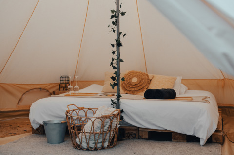 Gemütliches Glampingzelt mit Doppelbett, Dekor und Korb bei Glamping La Ferme in Westflandern.