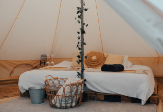 Gemütliches Glampingzelt mit Doppelbett, Dekor und Korb bei Glamping La Ferme in Westflandern.