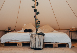 Einladendes Glampingzelt mit komfortablem Bett, Holzelementen und stilvollen Details in Westflandern.