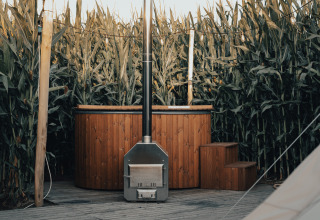 Alojamiento glamping con bañera de madera y terraza, rodeado de maizales en Glamping La Ferme, Flandes Occidental.