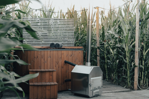 Bain à remous en bois et sauna extérieur entourés de maïs au Glamping La Ferme en Flandre-Occidentale, Belgique.