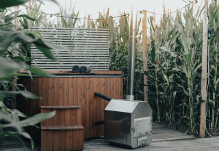 Outdoor wooden hot tub and sauna among cornfields at Glamping La Ferme glamping tents, West Flanders, Belgium.