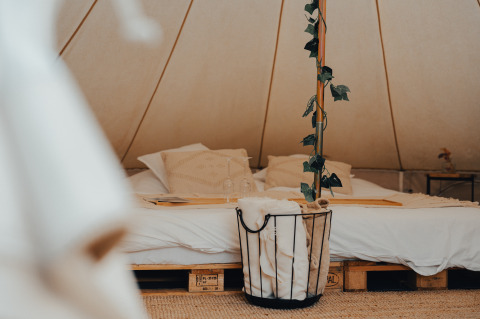 Gemütliche Glamping-Unterkunft mit Doppelbett, weicher Bettwäsche und Pflanzen im Zelt in Westflandern.