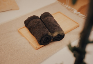 Zwei gerollte dunkle Handtücher auf einem Holztablett, gesehen bei Glamping La Ferme in Westflandern.