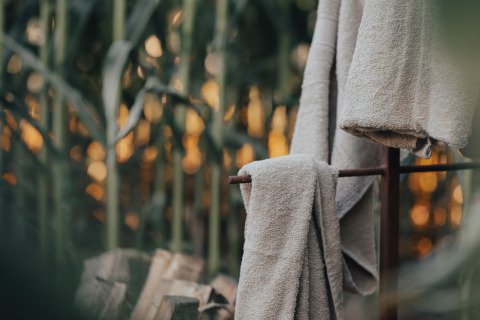 Soft towels hanging outdoors with sunset and greenery at Glamping La Ferme - Glampingtenten West-Vlaanderen.