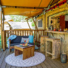 Comfortable glamping accommodation with a covered deck and wooden furniture at Per Amore Del Vino in Lombardy.