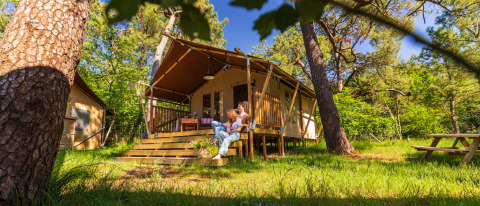 Gezin ontspant buiten bij een safaritent op Per Amore Del Vino glamping in Lombardije, omringd door groen.