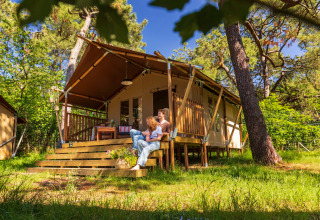 Famiglia si rilassa davanti a una tenda safari a Per Amore Del Vino glamping in Lombardia, immersi nel verde.