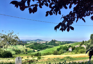 Blick auf grüne Hügel, Weinberge und ein Dorf von Per Amore Del Vino - Safaritenten Lombardije Campingplatz.