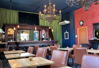 Elegant restaurantindretning med brune stole, lysekroner og grønne gardiner på Per Amore Del Vino i Lombardiet.