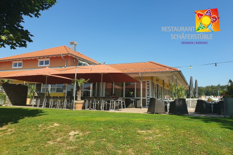 Terrazza soleggiata del ristorante presso Camping & Vakantiepark Orsingen - Stacaravans Baden-Württemberg con ombrelloni.