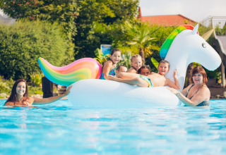 Kinderen en volwassenen hebben plezier op een grote eenhoorn opblaas in het zwembad bij Vakantiepark Orsingen.