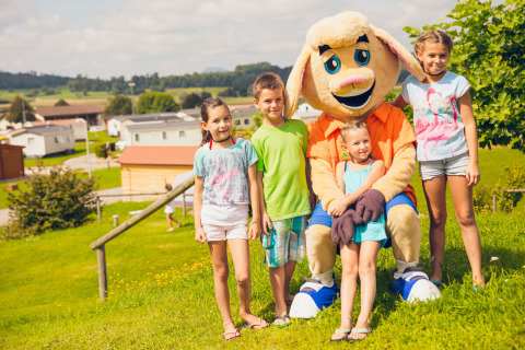 Children posing with a mascot on the grass at Camping & Vakantiepark Orsingen - Stacaravans Baden-Württemberg.