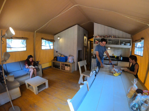 Personen ontspannen en maken eten klaar in een glampingtent bij Camping Alf - Safaritenten Rijnland-Palts.
