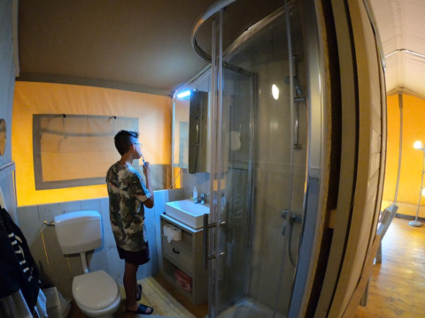 Joven cepillándose los dientes en el baño de una lujosa tienda tipo safari en Camping Alf - Safaritenten Rijnland-Palts.