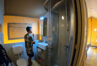 Young man brushing his teeth in the bathroom of a luxury safari tent at Camping Alf - Safaritenten Rijnland-Palts.