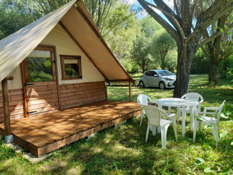 Glamping at Gorges de la Méouge with hut lodge, outdoor plastic chairs, table, and car in Provence.