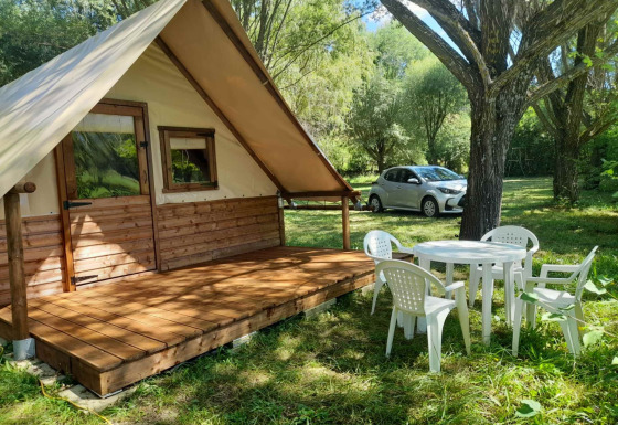 Glamping ved Gorges de la Méouge med hytte, plastikmøbler og bil i Provences naturskønne omgivelser.