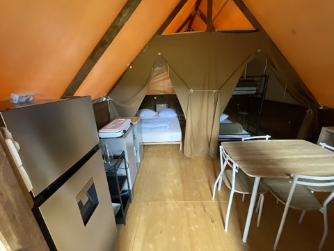Interior of a glamping hut at Gorges de la Méouge, Provence-Alpes-Côte d'Azur, with beds, table, and kitchenette.