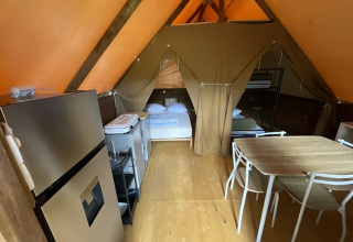 Innenansicht einer Glamping-Lodge in Gorges de la Méouge, Provence-Alpes-Côte d'Azur mit Bett und Esstisch.