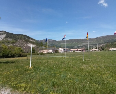 Cancha de voleibol al aire libre con banderas y vistas a las montañas en Gorges de la Méouge, Francia.