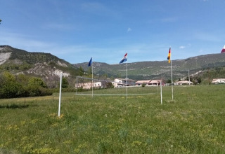 Outdoor volleyball court with flags and mountain scenery near Gorges de la Méouge glamping lodges.