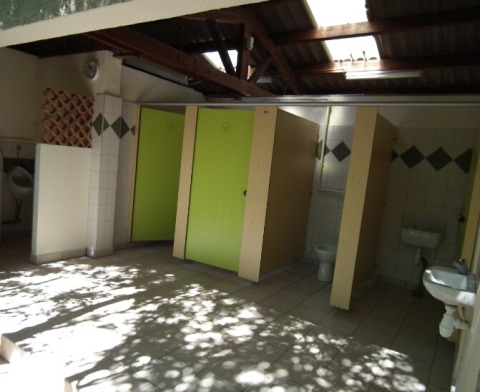 Bagno pubblico ai Gorges de la Meouge Hut Lodges con porte verdi e tetto parzialmente aperto.