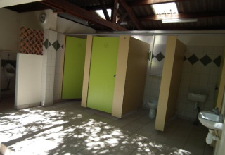 Bagno pubblico ai Gorges de la Meouge Hut Lodges con porte verdi e tetto parzialmente aperto.