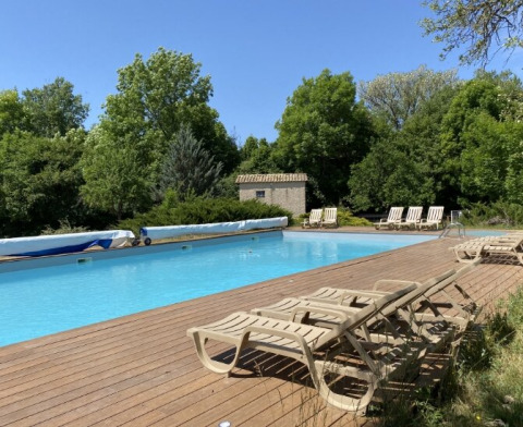 Udendørs swimmingpool omringet af liggestole og grønne træer ved Gorges de la Meouge - Hut Lodges i Provence.